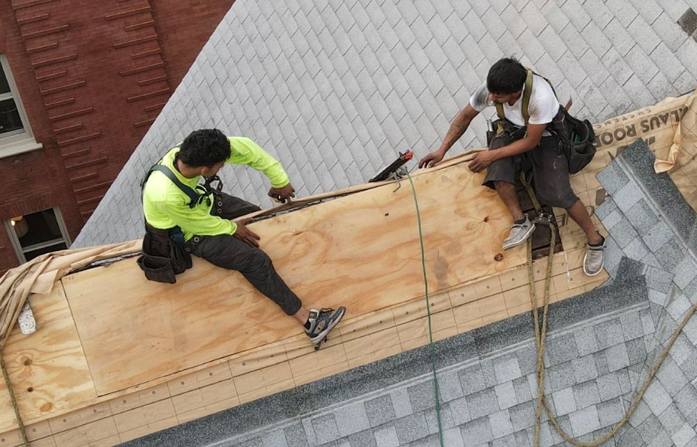 Roof-repair Two men patching a section of a roof.